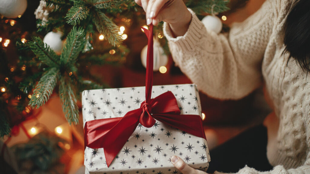 A woman unwrapping a Christmas gift.