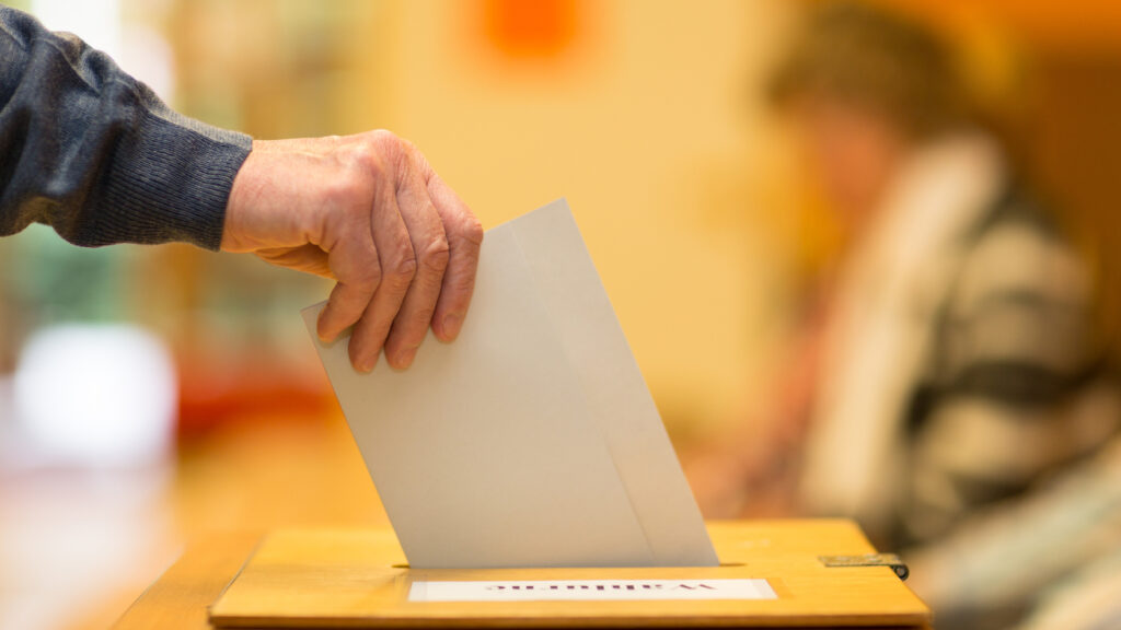 A man putting a ballot paper into a ballot box.