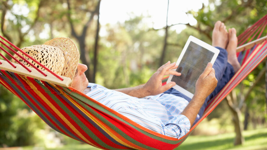 A man in a hammock using a tablet.