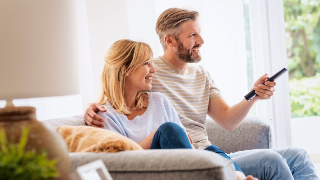 A couple sitting on the sofa to watch TV.