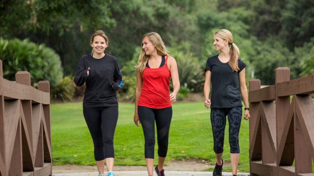 Three women in gym clothes walking over a bridge