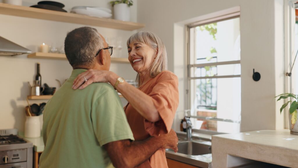 An older couple dancing together at home.