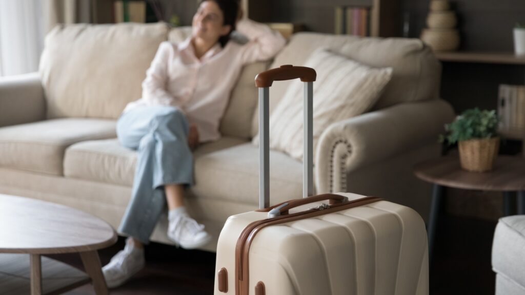 A suitcase with a woman sitting in the background.