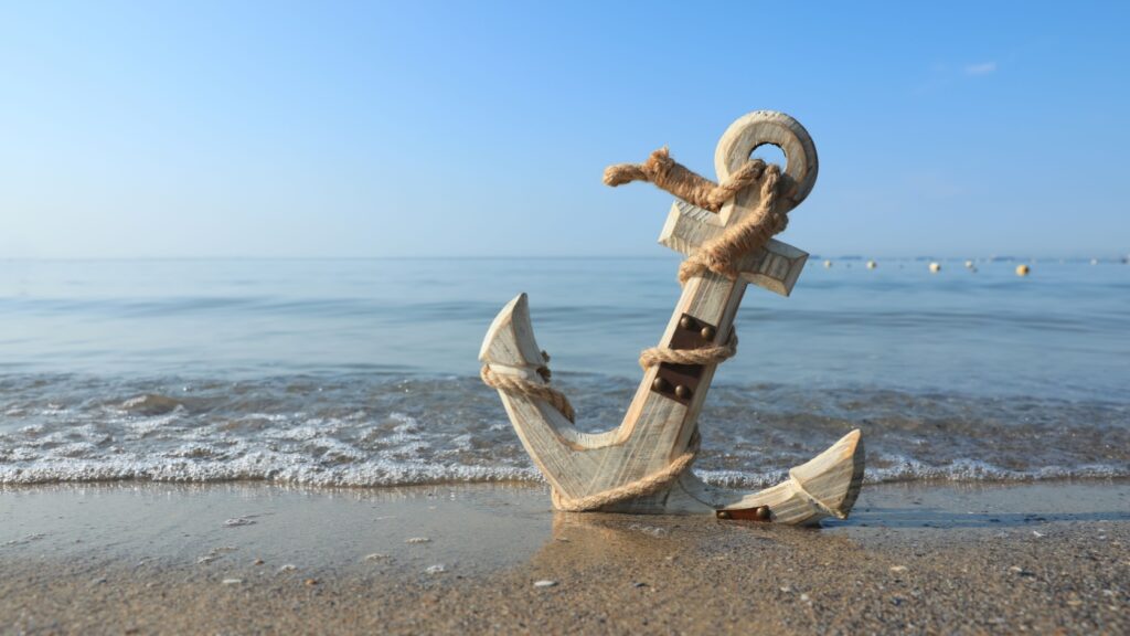 A wooden anchor on a beach.