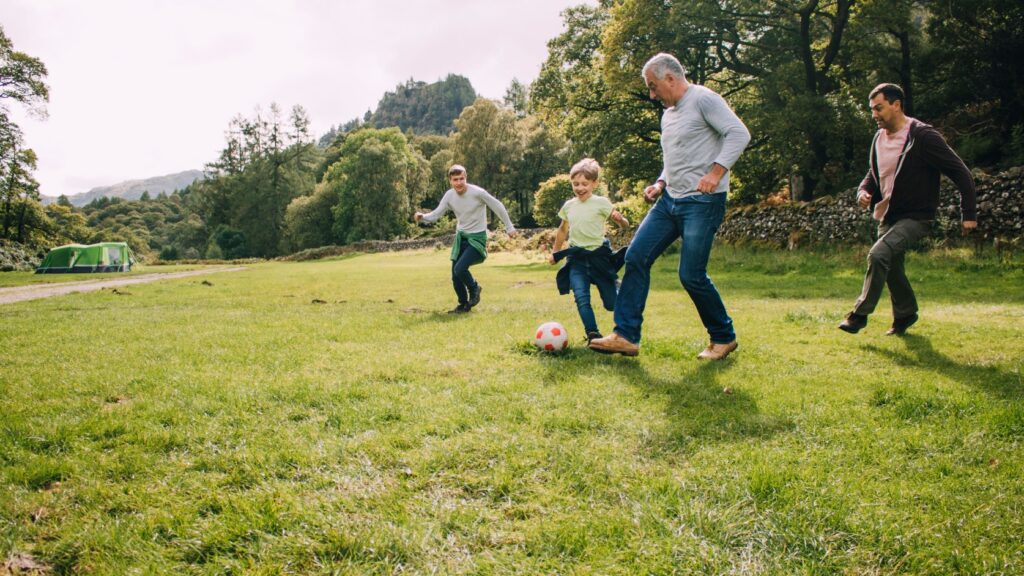 Multi-generational family playing football in a park.