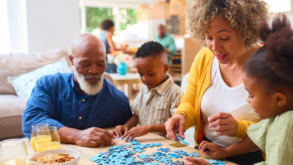 Grandparents doing a jigsaw with their two grandchildren.