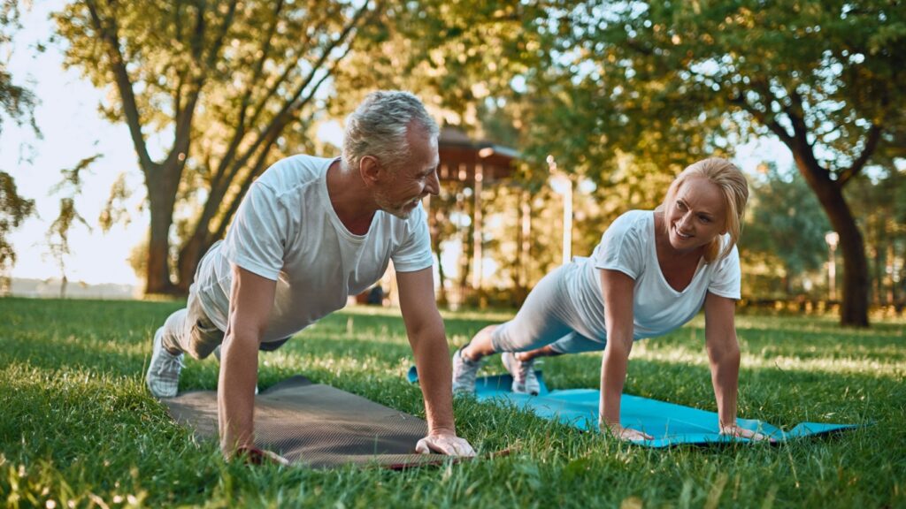 A couple doing yoga in a park.