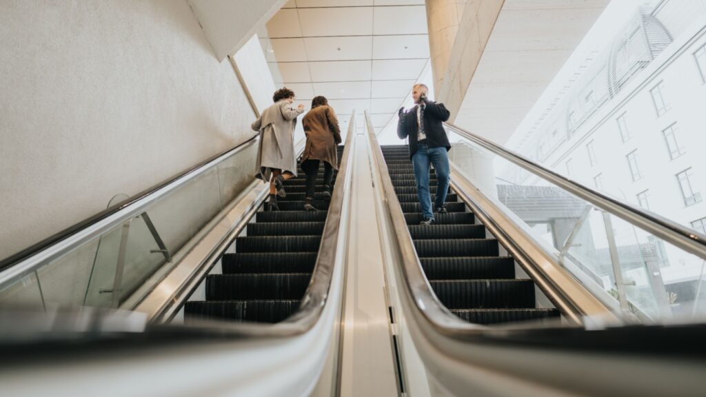 People using escalators in an office building.