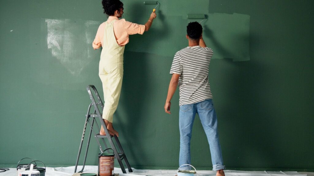 A couple painting a wall in their home.
