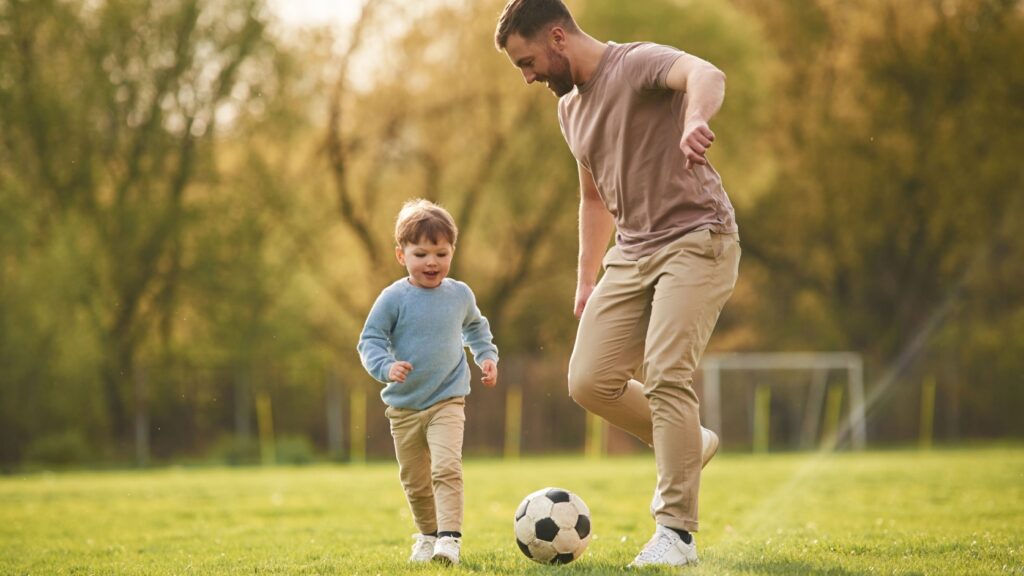 A father playing football with his young son.