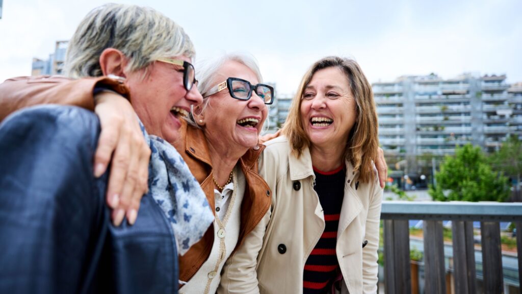 Three women with the around each other laughing.