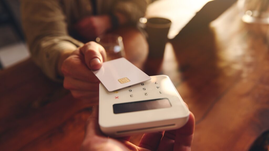 A person using their debit card to pay in a café.