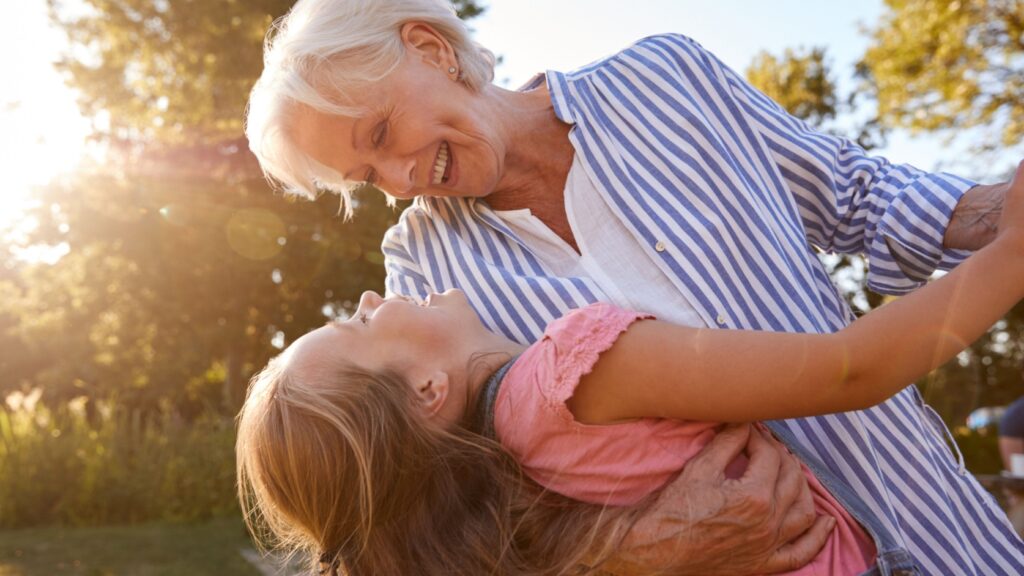 A grandmother playing with her granddaughter outside.