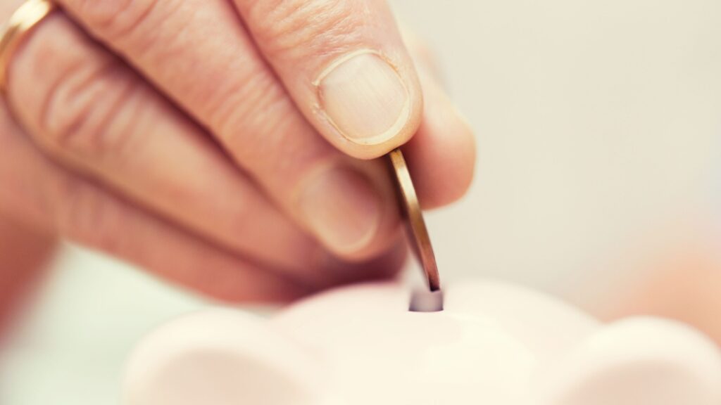 A person putting a coin into a money box.