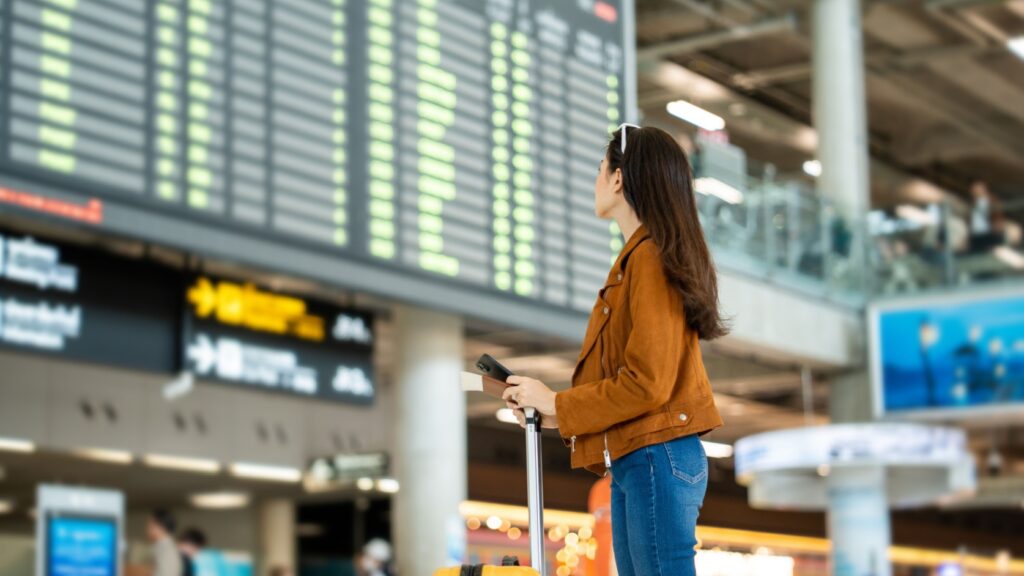 A woman looking at a departure board in an airport.