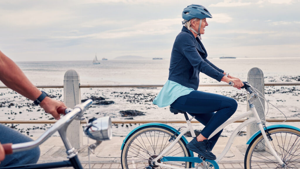 A woman cycling along a beachfront.